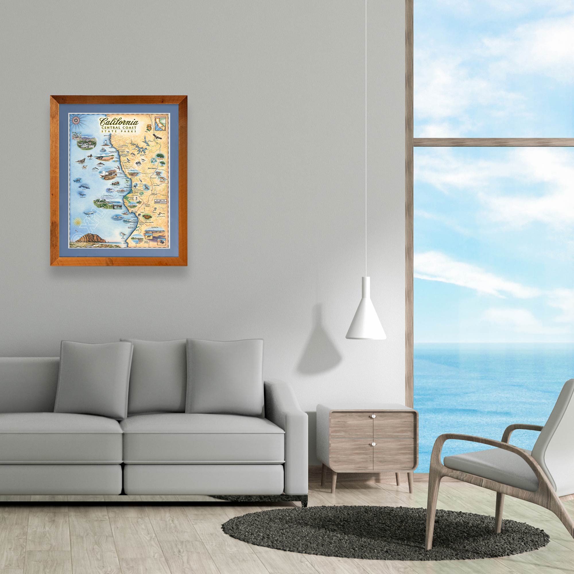 California Central Coast State Hand-Drawn Map framed in a Montana Flathead Lake reclaimed larch wood frame and blue mat. The map is hanging above a gray couch with ocean views.