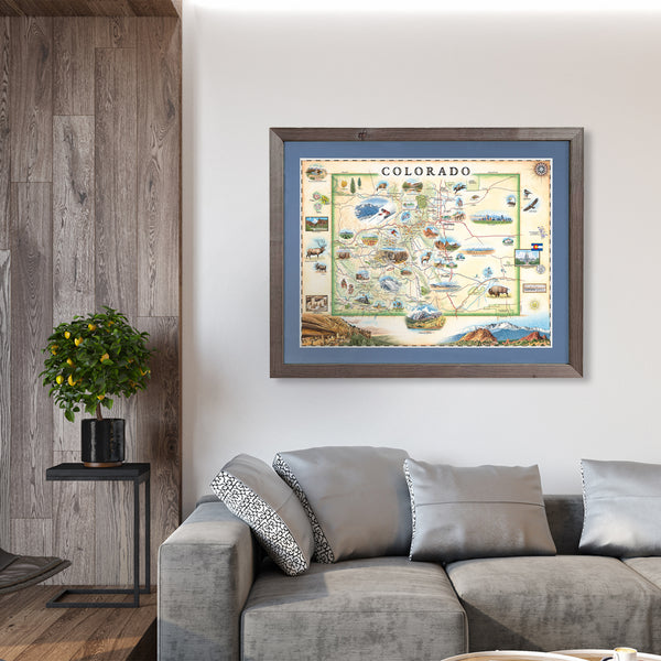 Colorado State hand-drawn map in a gray frame with blue mat The map is hanging on a wall above a gray couch. 