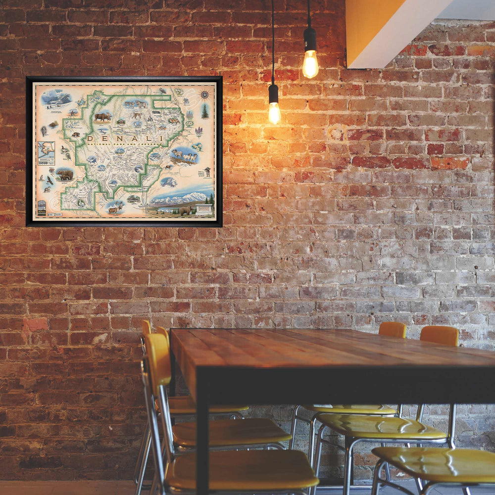 Denali National Park hand-drawn map in a black frame hanging on a brick wall over a kitchen table. 