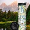 Grand Teton National Park Map travel drinkware with snow cap mountains and a forest of pine trees with a pond in the background. Map illustrations include flora and fauna of the area, such as grizzly bears, moose, coyote, lupine, and longleaf phlox. Illustrations of places include snake river overlook, jenny lake, and Colter Bay Village.