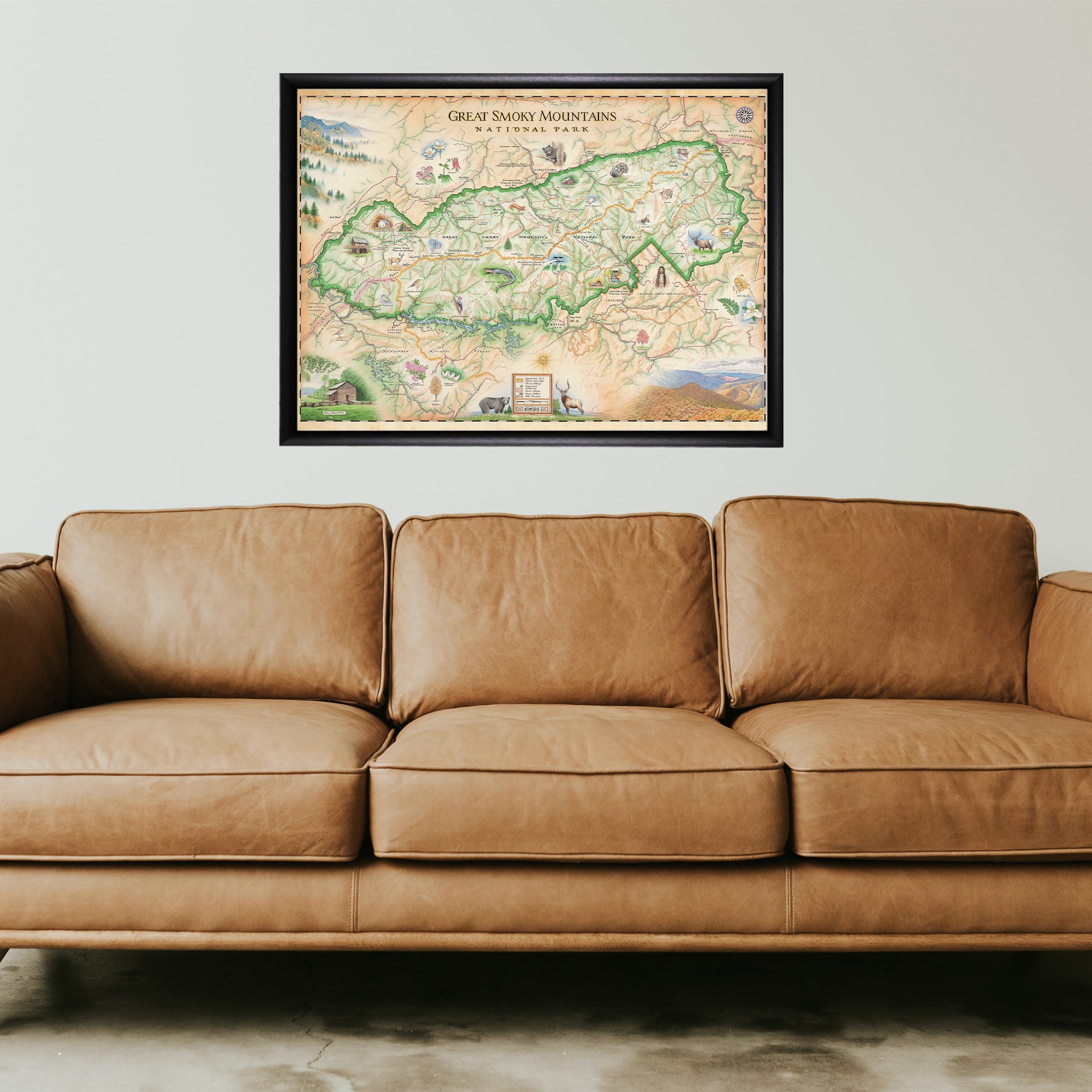 Great Smoky Mountains National Park framed hand-drawn map in a black frame hanging above a brown leather couch.