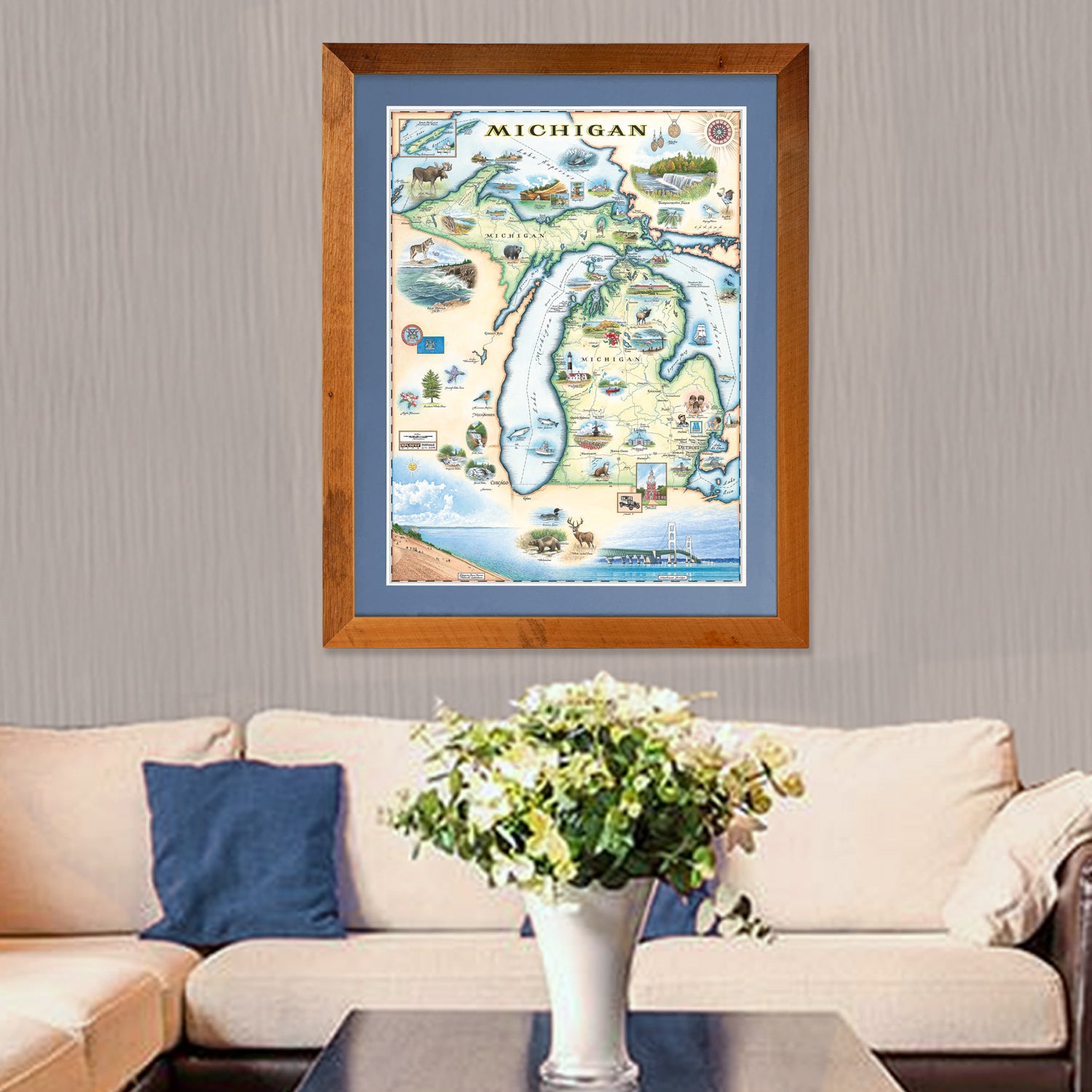 Xplorer Maps hand-drawn map of the state of Michigan hangs above a couch. The print is framed with a brown wooden frame.