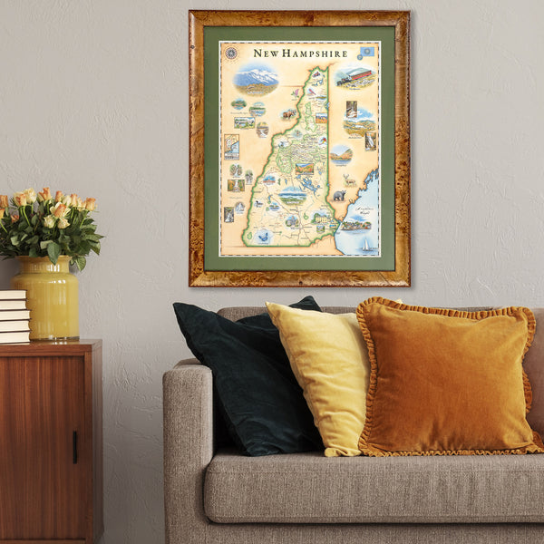 Xplorer Maps hand-drawn state map of New Hampshire hangs in a living room above a gray couch. 