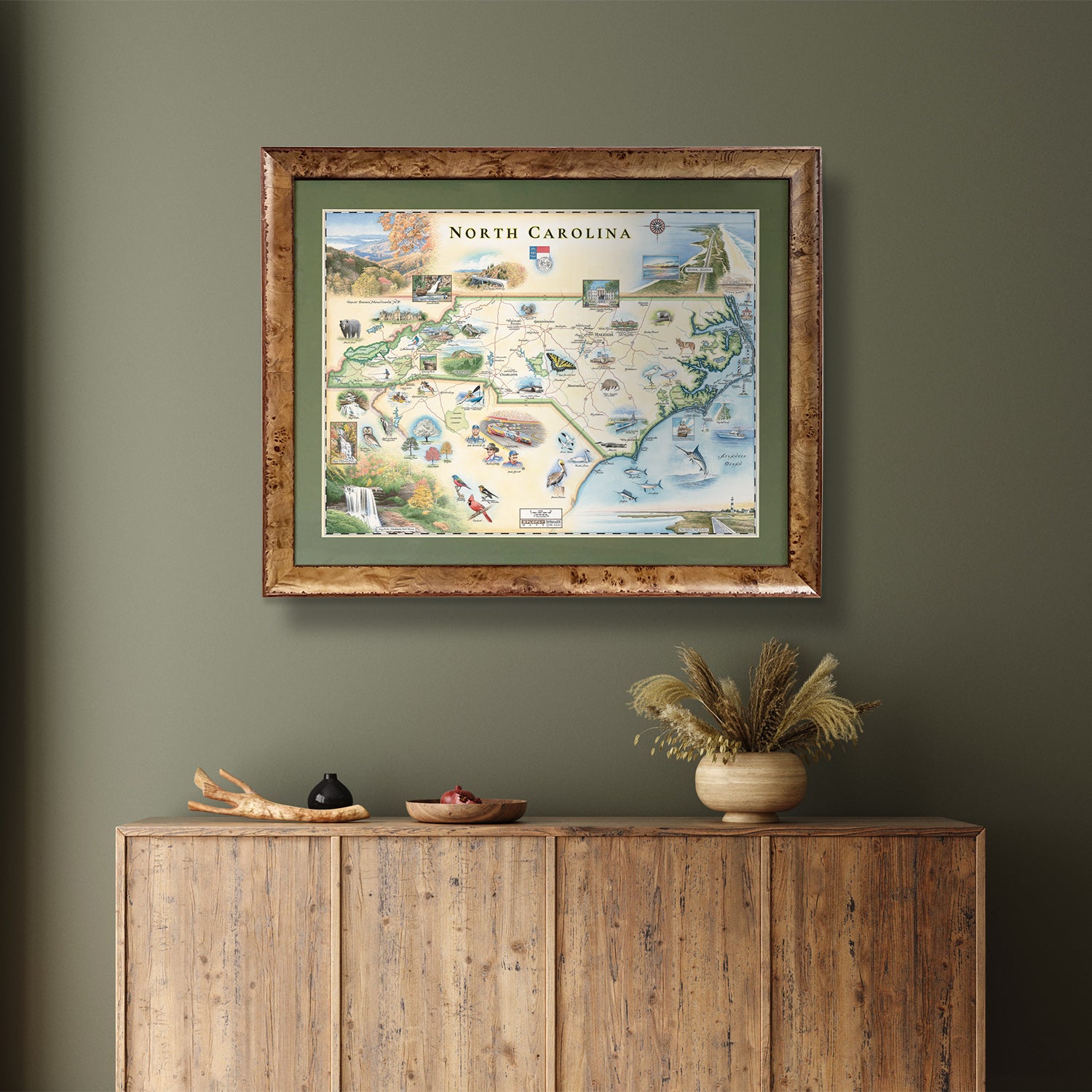 Xplorer Maps state map of North Carolina hangs on a greem wall above a table.