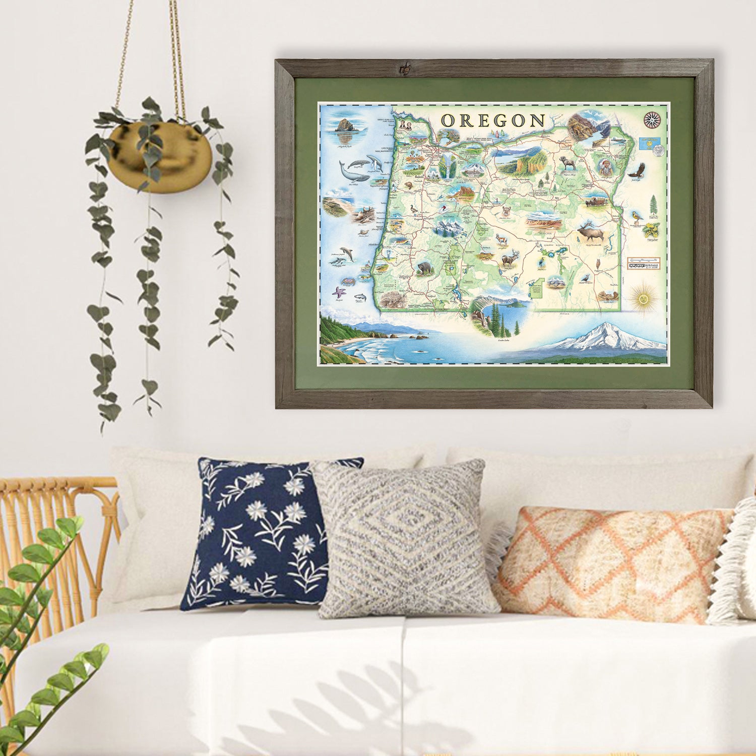 Xplorer Maps state map of Oregon hangs in a living room above a couch, a plant hangs from the ceiling beside the framed print.