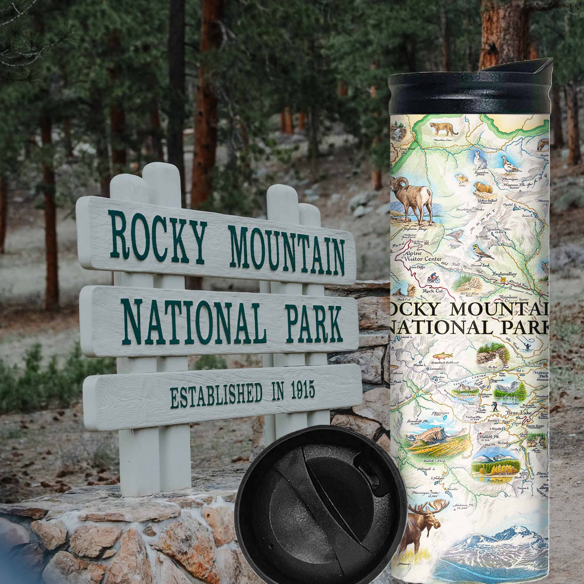 Rocky Mountain National Park Map 16 oz Travel Bottle. In the background is the Rocky Mountain National Park Sign with pine trees by it. The map features illustrations of places like Trail Ridge Road, Mount Ganby, Estes Park, and the Alpine Visitor Center. Flora and fauna include bobcats, snowshoe hares, Indian paintbrushes, and wild roses. 
