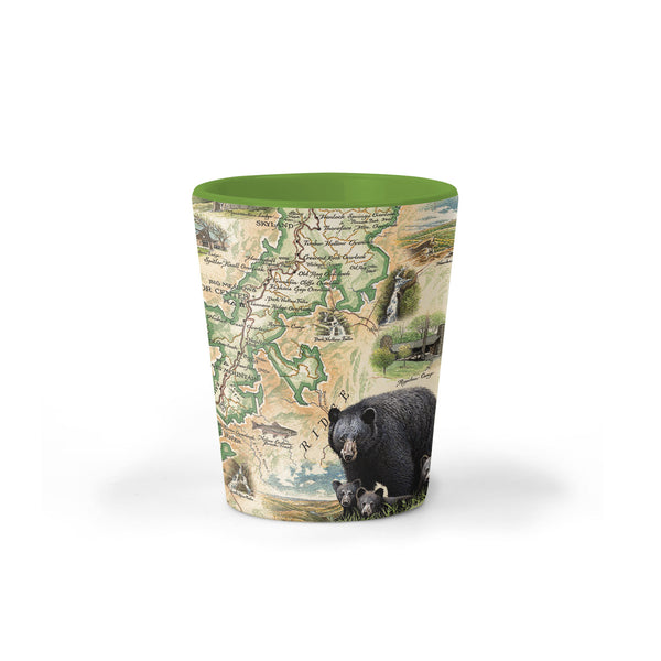 Shenandoah National Park Map Ceramic shot glass by Xplorer Maps. The map includes illustrations of places such as Skyline Drive, Byrd Visitor Center, and Big Meadows Lodge. Flora and fauna include bobcats, wild turkeys, trillium flowers, a dogwood tree, and a black bear with cubs. 