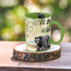 "Green 16 oz Shenandoah National Park Map Ceramic Mug with handle, on log coaster, on picnic table.